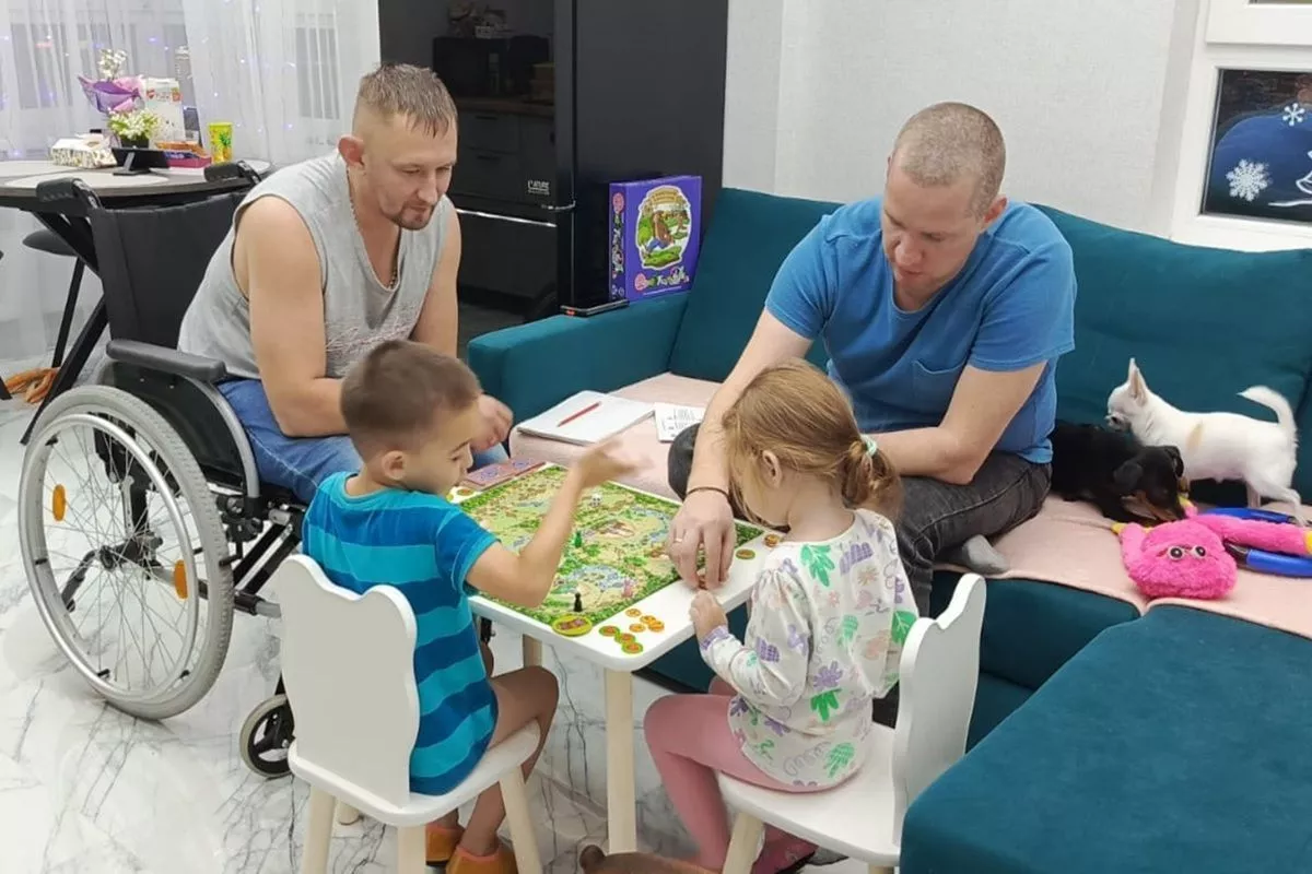 Игорь Филиппов с приятелем и детьми за настольной игрой.