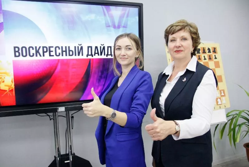 Директор школы № 18 Галина Власова (справа) и руководитель школьной «Точки роста», учитель Светлана Карпачевская возле экрана с заставкой еженедельного дайджеста, который выпускают учащиеся.