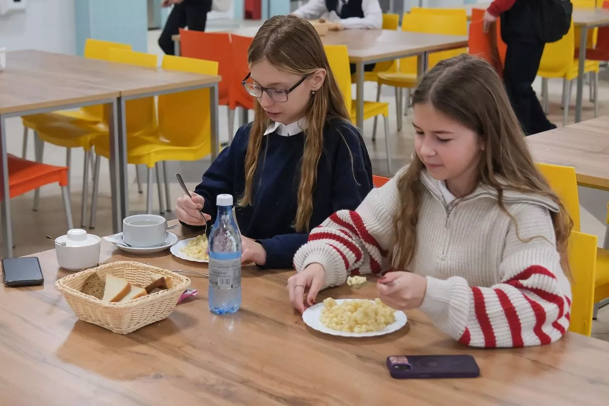 Ребята едят за новыми столами, сидя на ярких удобных стульях.