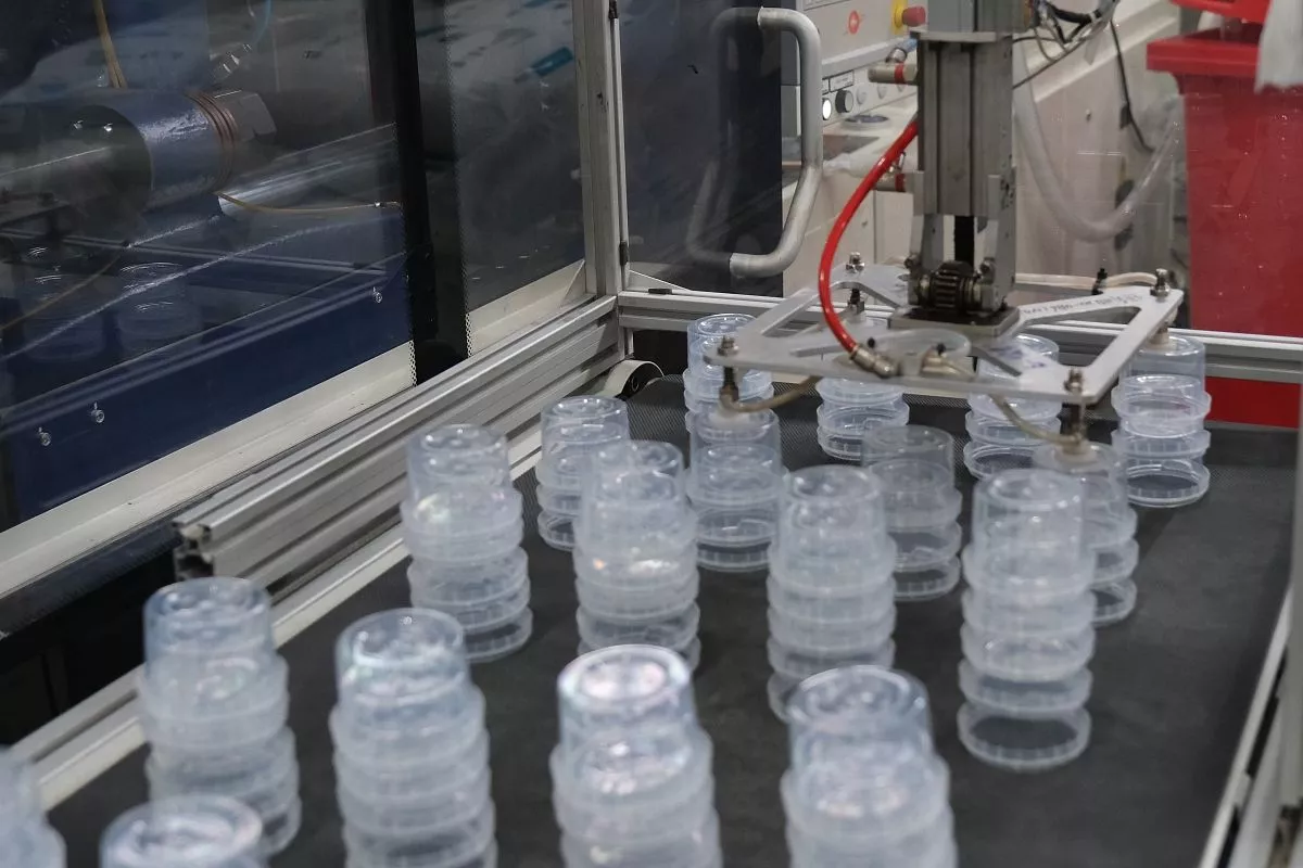 Делать пластиковые ведерки помогают роботы-манипуляторы.