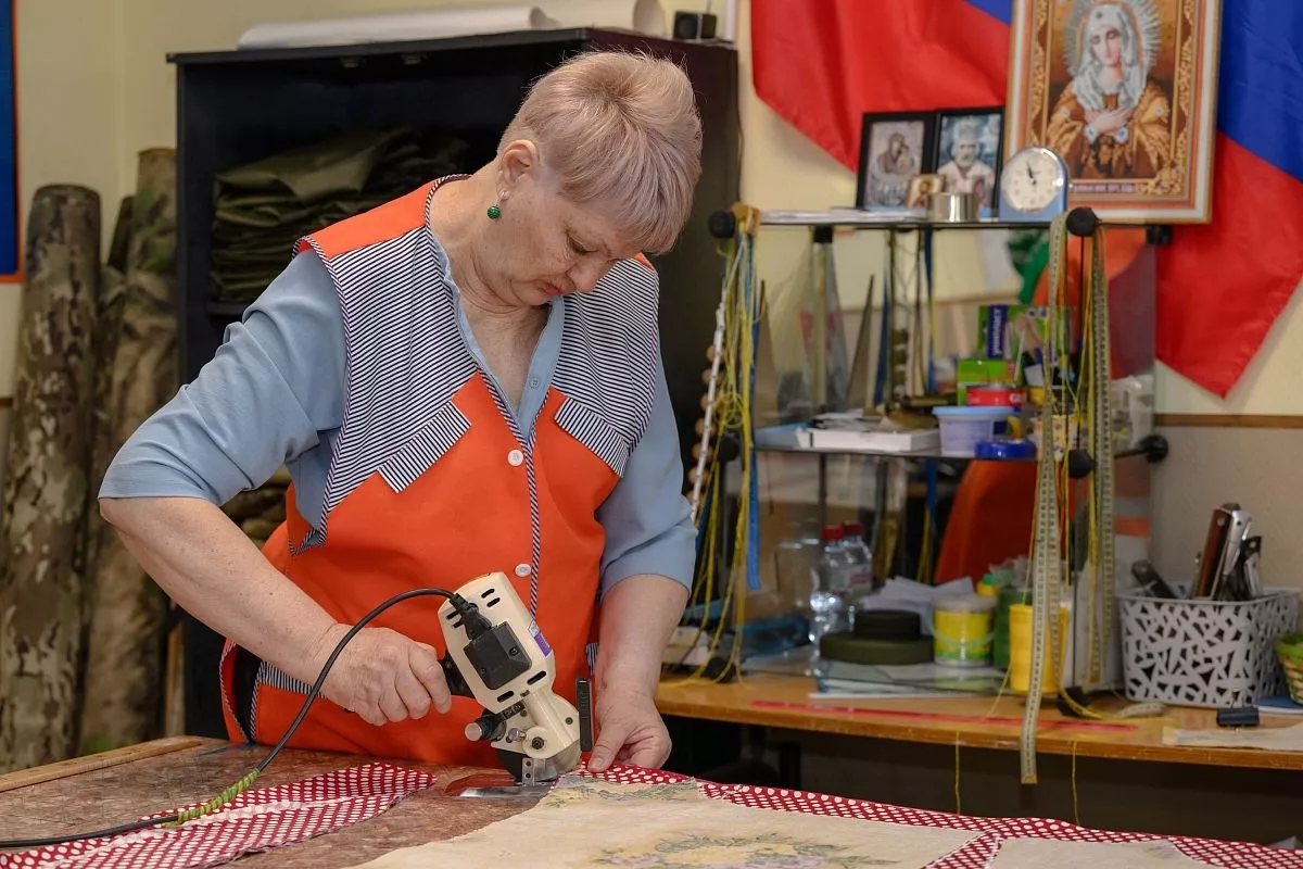 Валентина Орлова ловко управляется с аппаратом для раскройки ткани. 