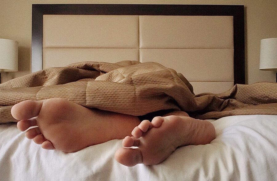 Не получилось в постели. Ноги из под одеяла. Мужские ноги на кровати. Мужские ноги под одеялом.