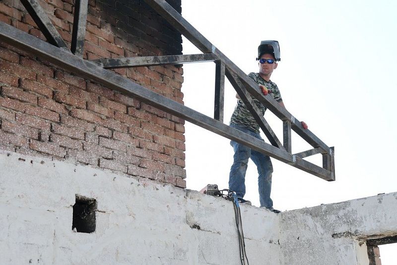 В Краснодаре крышу пострадавшей от огня 8-этажки по ул. Российской начали накрывать профнастилом