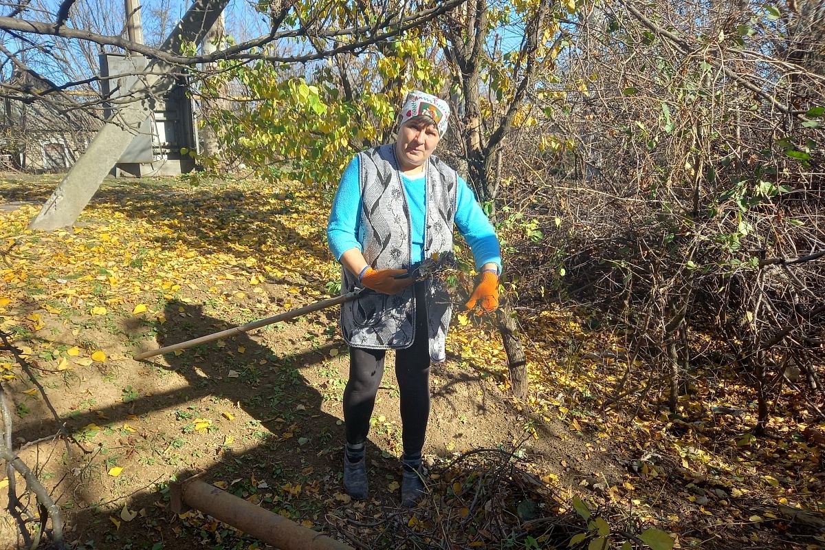 Жительница поселка Трудовские Людмила убирает возле своего дома. В него уже дважды прилетали украинские снаряды. 
