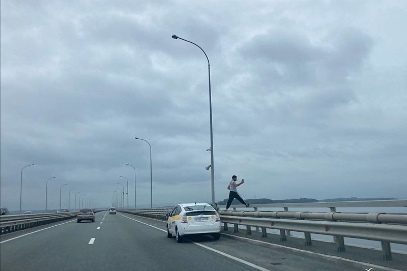 Во Владивостоке таксист забрался на бордюр моста ради красивого кадра моря